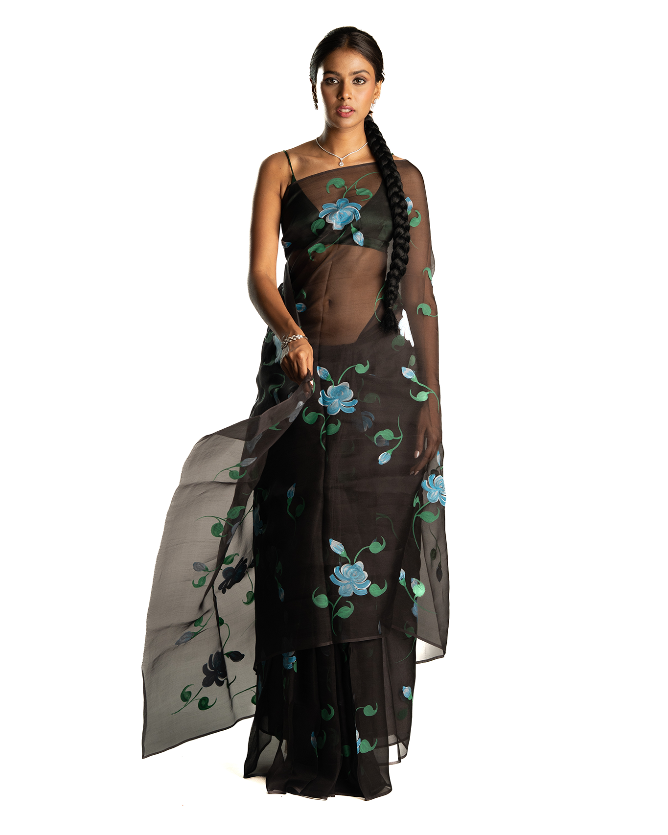 Woman wearing a black saree with floral blue patterns on a white background