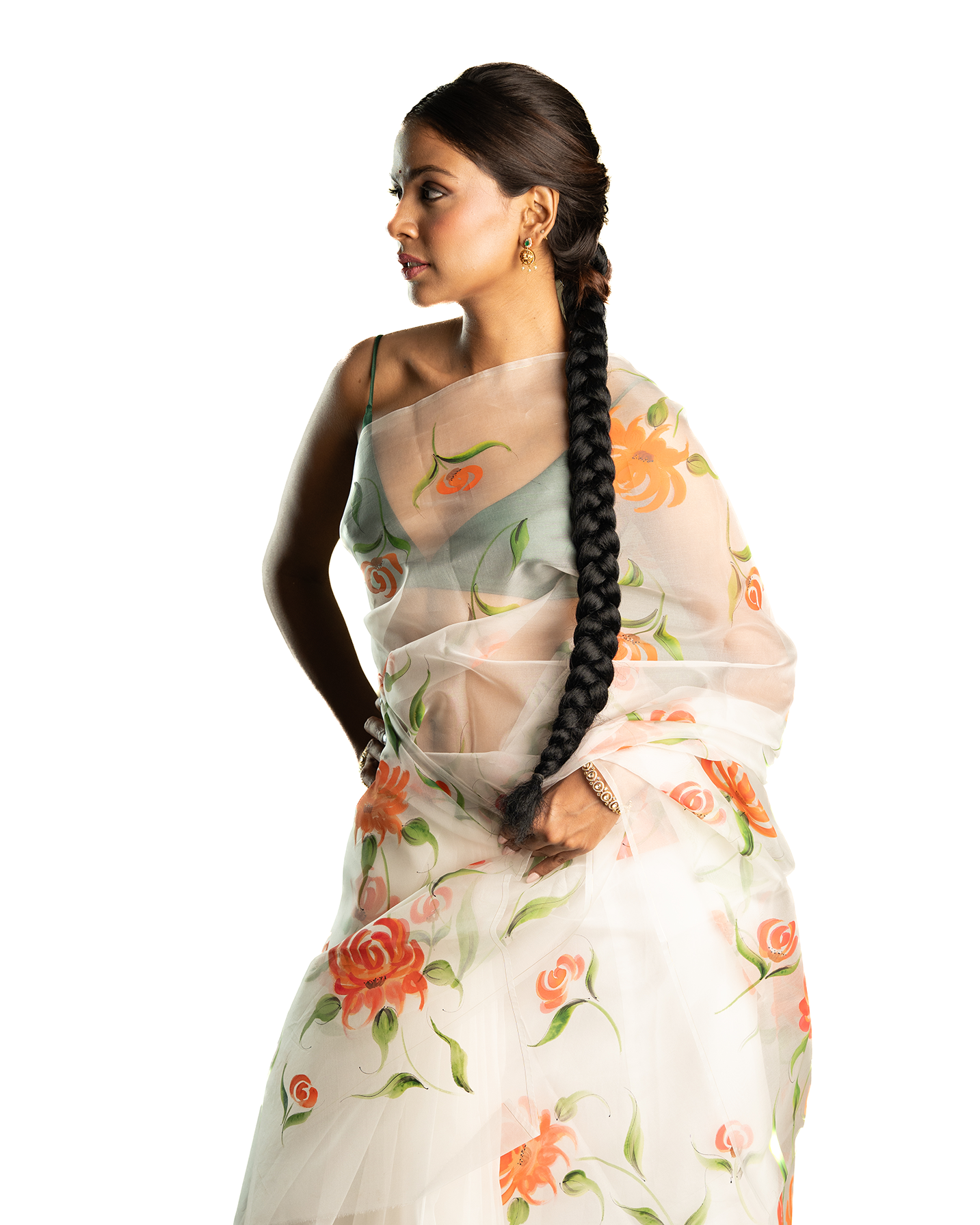 Woman wearing a floral saree with a long braid on a white background