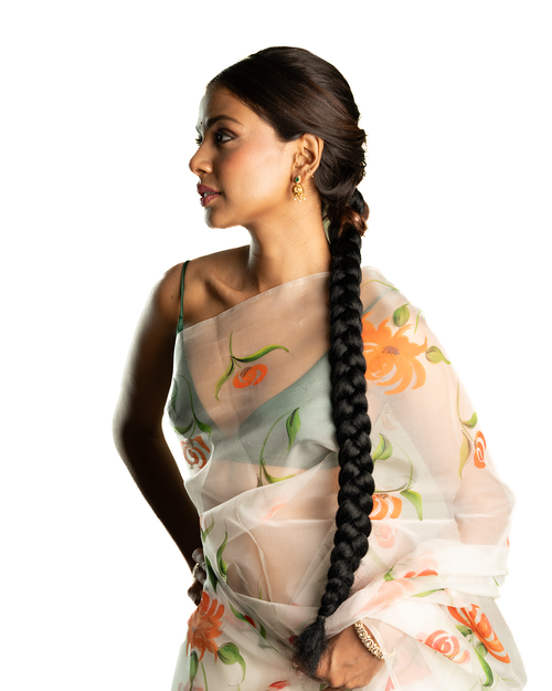 Woman wearing a floral saree with a long braid on a white background