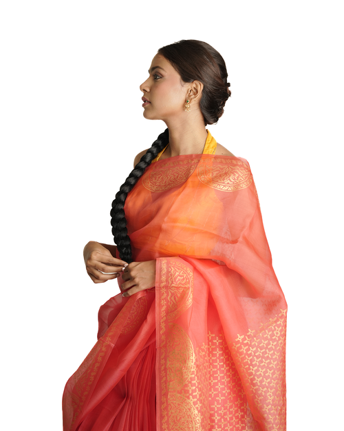 Woman wearing a vibrant orange and red saree with a white background