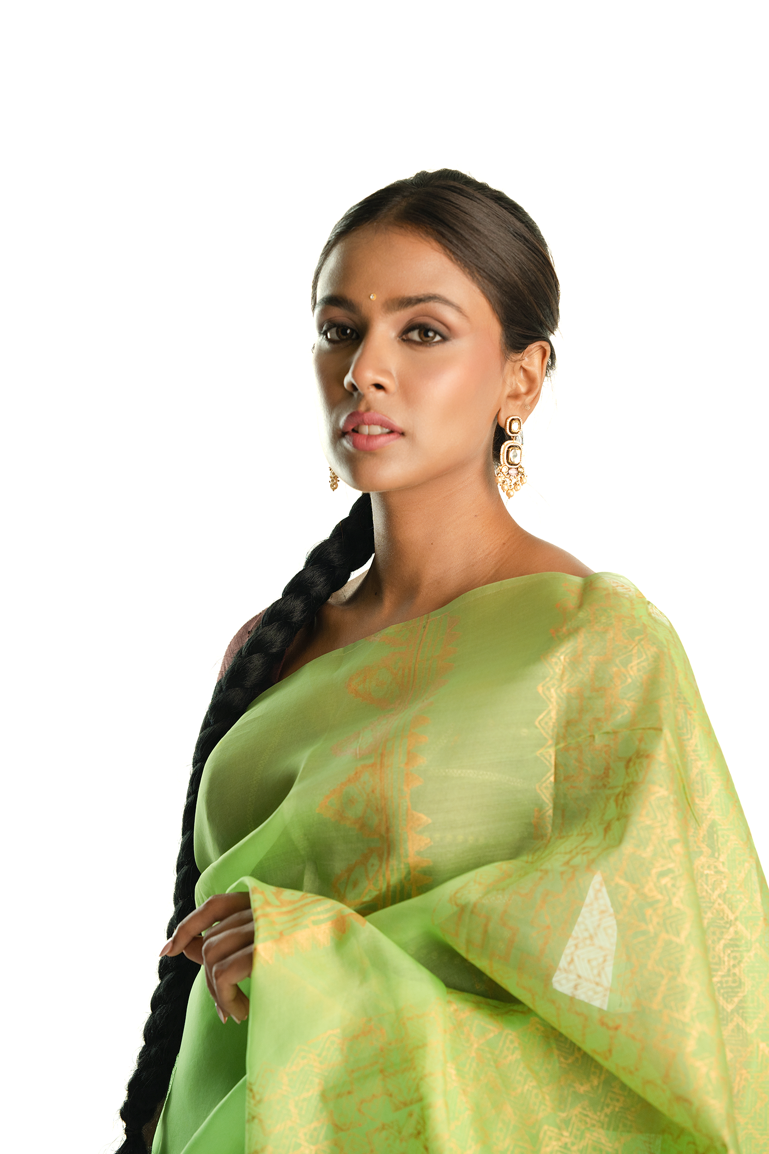 Woman wearing a light handblock green saree with a white background.