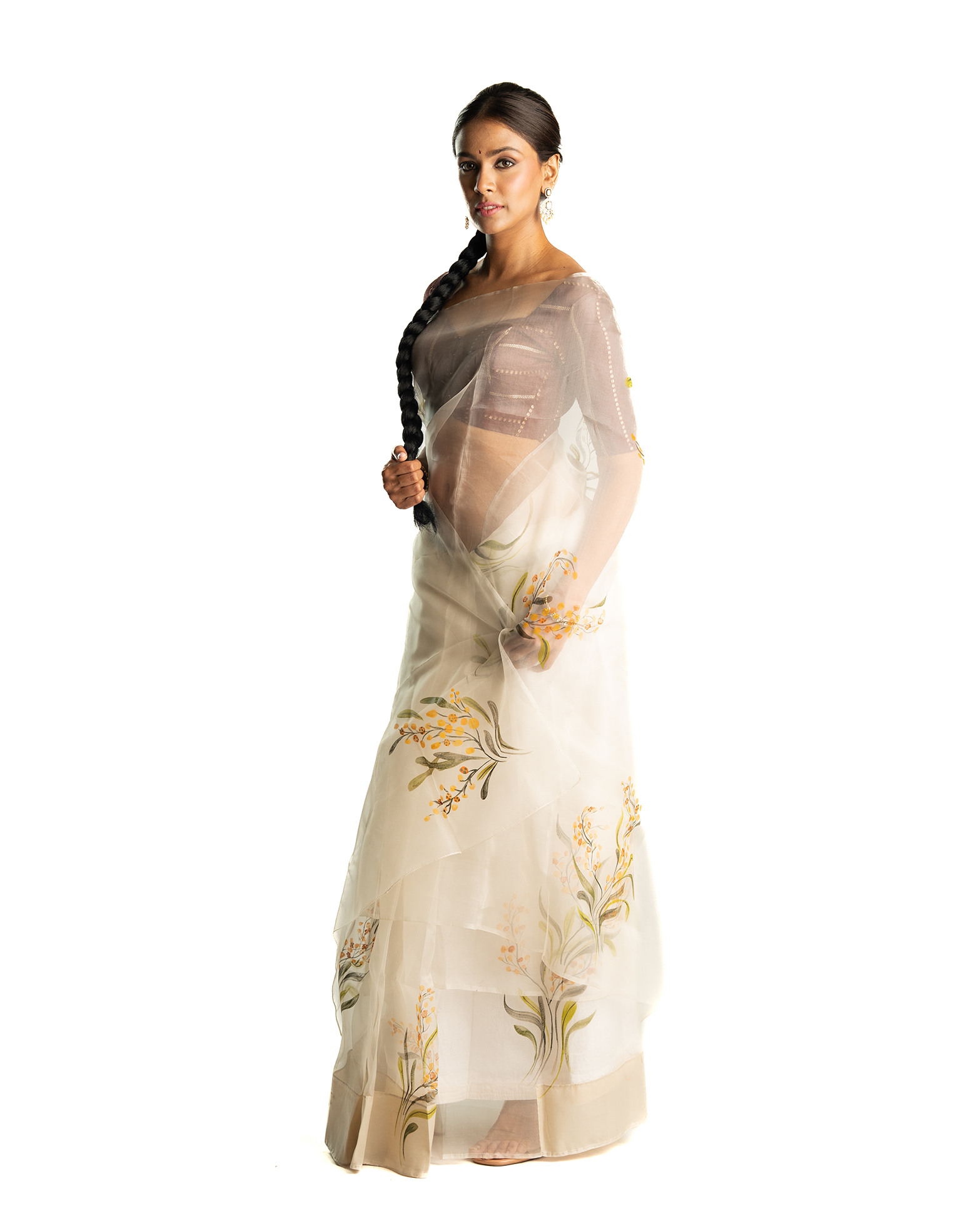 Woman wearing a beige saree with floral patterns on a white background