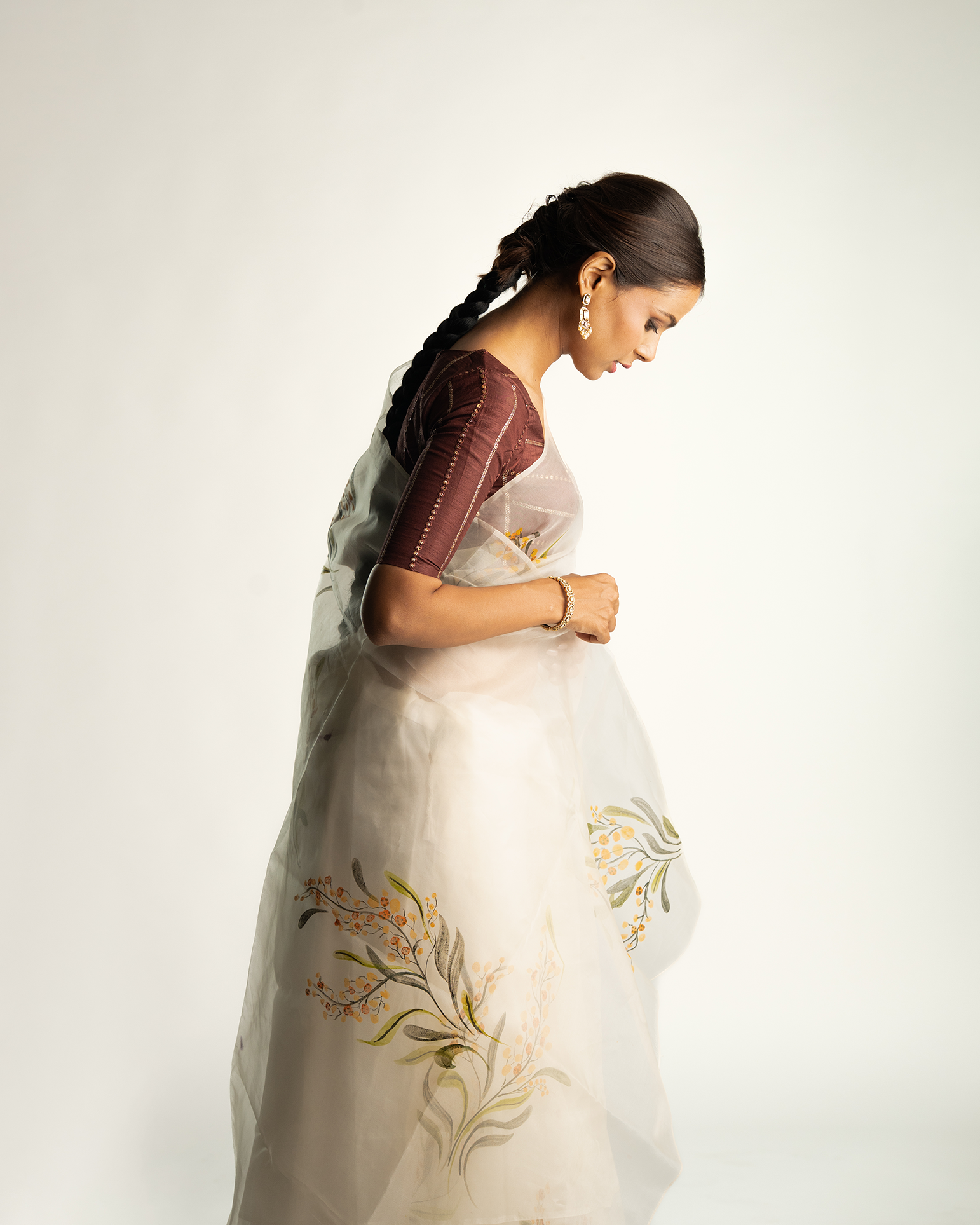 Woman wearing a traditional saree with floral embroidery on a plain background