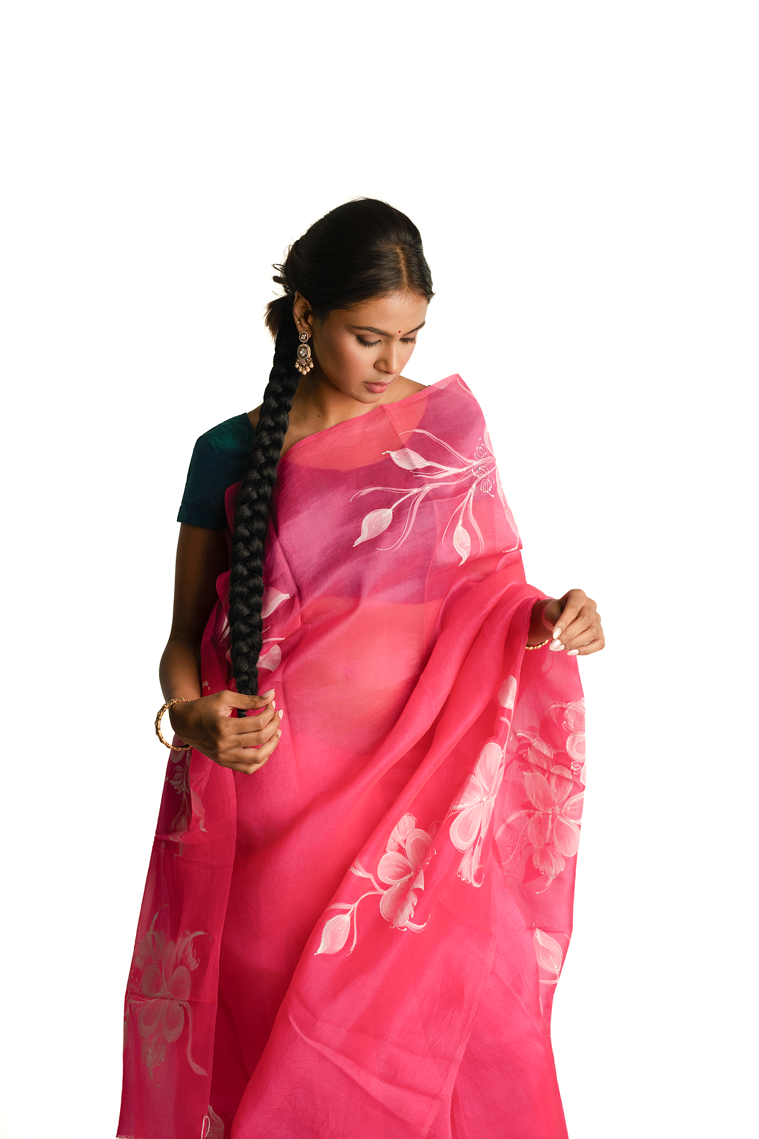 Woman wearing a pink saree with white floral patterns on a white background