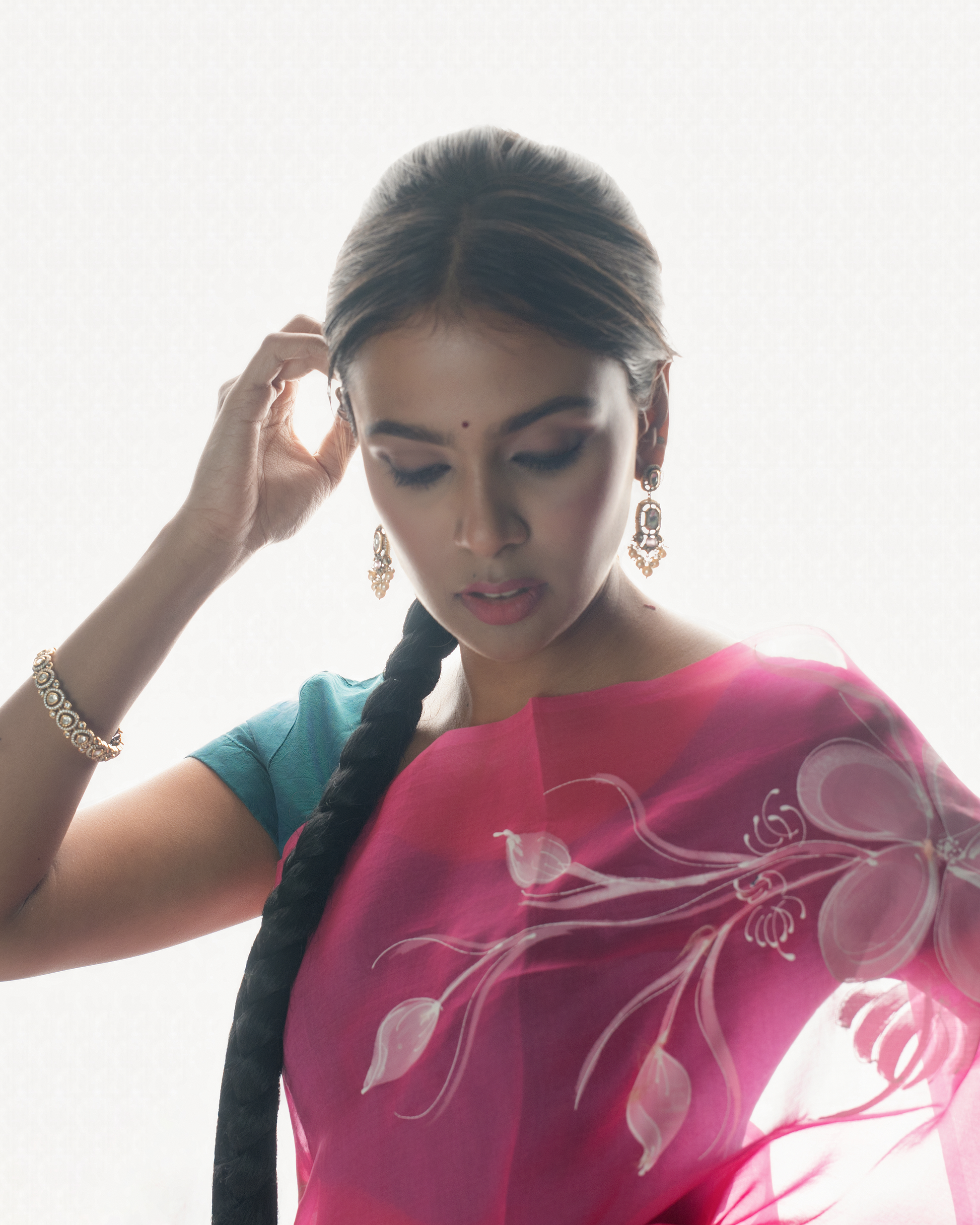 Woman wearing a pink saree with floral patterns against a light background
